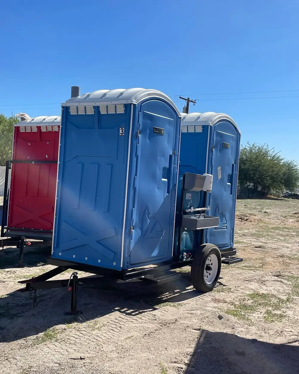 Porta potties strapped on a Sean Rental Works delivery trailer