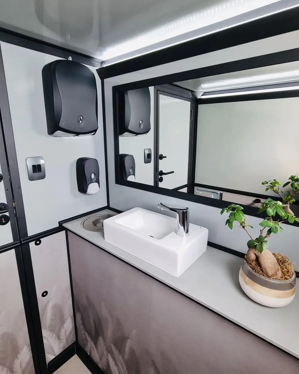 Restroom trailer vanity with vessel sink and lit mirror